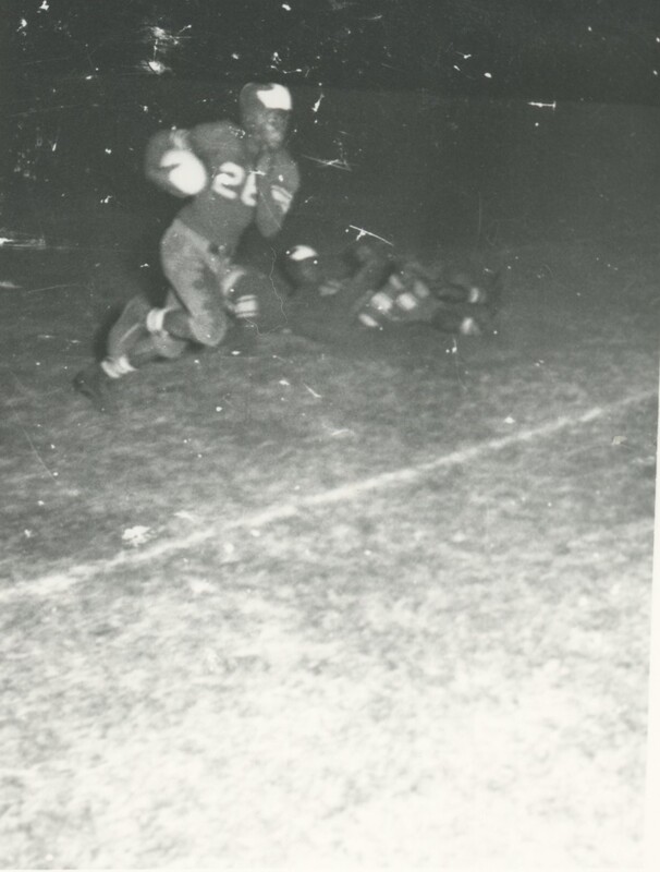 Two football players on a field in the middle of a game.