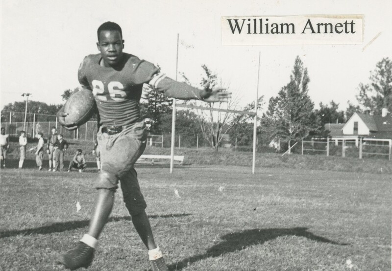 A young person holding a football on the field.