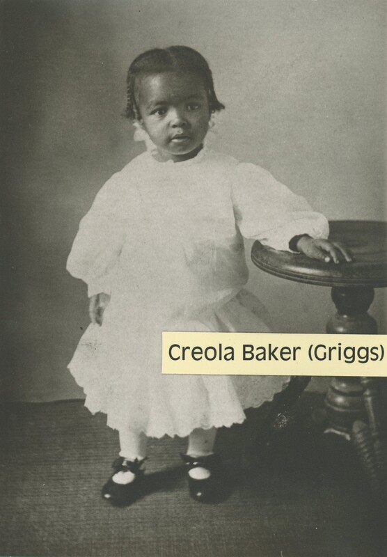 Small child standing next to a side table.