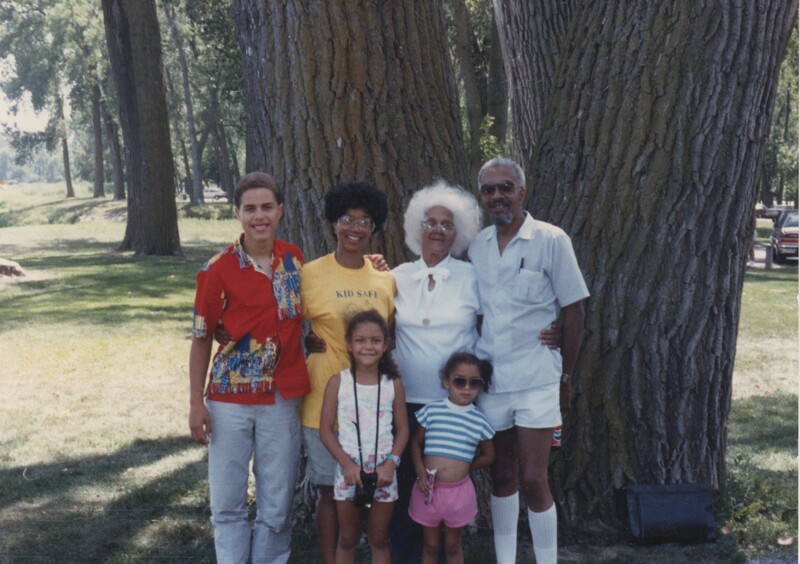 A family of six standing for a photo in front of a large tree.