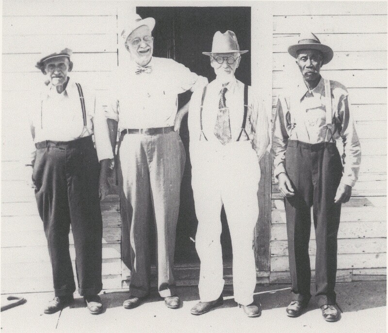 Four people are standing next to eachother in front of a doorway.