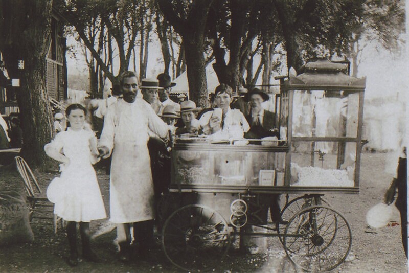 A person selling treats out of his vendor cart to children at an event.