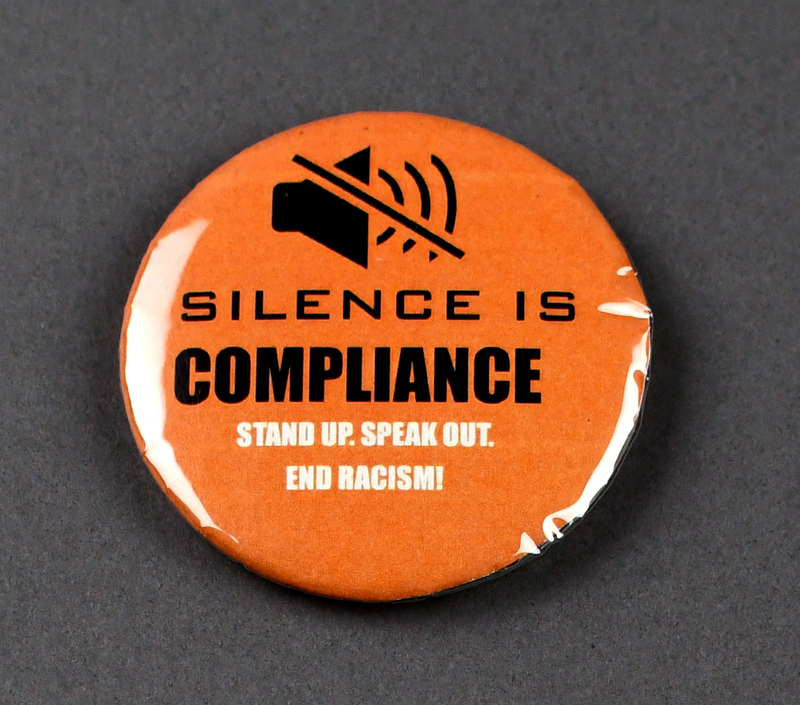 Button with safety pin clasp at posterior. Graphic at anterior printed on paper and crimped under transparent plastic covering. "SILENCE IS COMPLIANCE, STAND UP. SPEAK OUT. END RACISM!" in black and white lettering on orange background. Black loudspeaker with slash through above.    

Button made and sold/distributed by Amani Community Services during the 2020 George Floyd Protests in Waterloo. Amani community services is a domestic violence and sexual assault prevention agency serving African Americans in Black Hawk and Linn Counties with offices in Waterloo and Cedar Rapids. 
