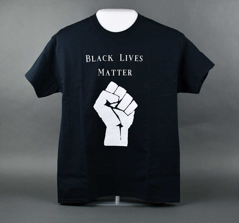 Crew-necked short-sleeve t-shirt of black cotton. Machine-stitched. “BLACK LIVES MATTER” in white over a stylized fist printed in white at center anterior.   

Worn by Organizer Joyce Levingston during the 2020 George Floyd Protests in Waterloo, Cedar Falls, and the surrounding area.  Levingston herself organized (with others) the May 29 march from Veterans Memorial Hall to Lincoln Park in Waterloo.  Waterloo Courier photos depict Levingston in the t-shirt at the June 6 vigil at Overman Park, Cedar Falls.  T-shirt also worn at the June 20 march from Clay St. to Overman Park in Cedar Falls.

From donor Joyce Levingston:

“When I heard George Floyd call out to his momma knowing he was going to lose his life, my heart shattered. It was at that moment that I knew in my lifetime I had seen this happen too much to my own. After hearing about Breonna Taylor and seeing what happened to George Floyd and many others in my lifetime I looked at my three daughters and my son and decided we need to come together in our community for all of our voices to be heard and mourn together for once instead of us carrying the weight on our own.  Rest in peace Breonna Taylor and rest in peace George Floyd.”