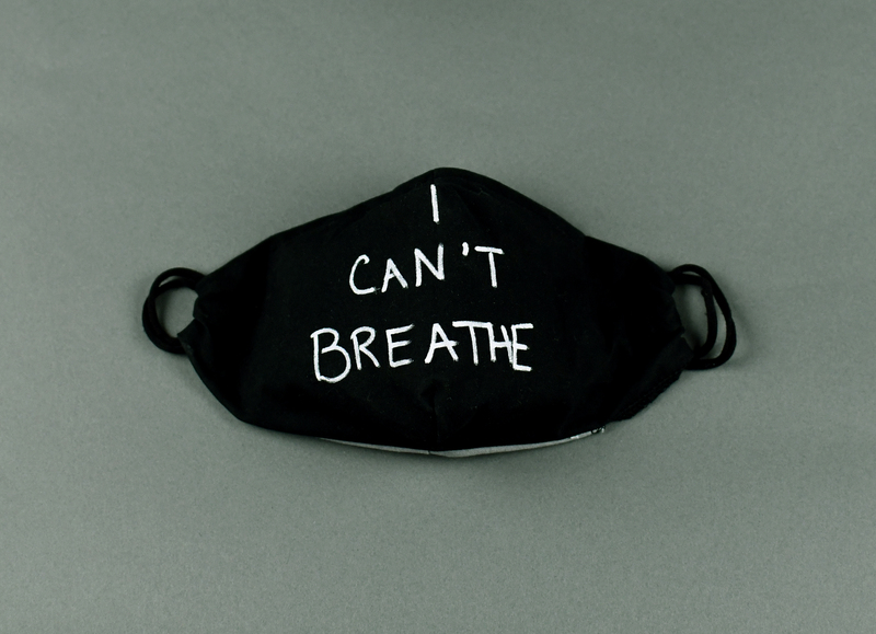 Covid mask of black fabric with orange fabric backing. Hand-made. Machine-stitched. “I CAN’T BREATHE” in white acrylic paint at center anterior.   

Mask made by Maggie Dvorak of Cedar Falls.  Worn by unidentified protestor at the May 29 march from Veterans Memorial Park to Lincoln Park in Waterloo, and in other demonstrations in June, 2020.

From donor Maggie Dvorak:

“I chose to contribute masks for several events in the Cedar Valley. These were events to bring community leaders and members together to show support for Black lives mattering, and to denounce systemic racism in our communities, and world wide.

Due to Covid 19, and my belief in the importance of doing our best to protect each other during a world wide pandemic, it was important to provide as many masks as necessary for participants to have available for use.

I hope to continue to donate and contribute my voice and my mask making abilities in any opportunity I am able. I will do this in hopes of supporting community health, and to support bringing an end to the systemic racism present in our world.”