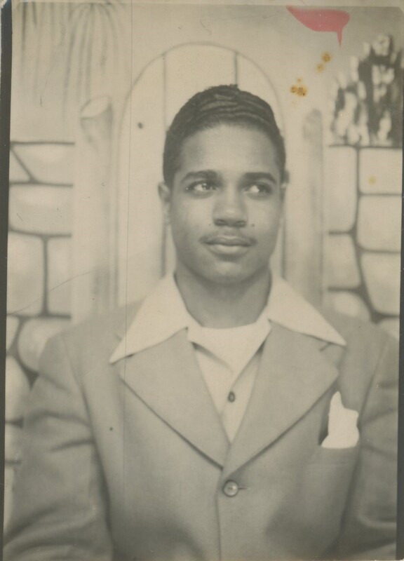 A young person in a suit looking to the side while having a photo taken from the chest up.