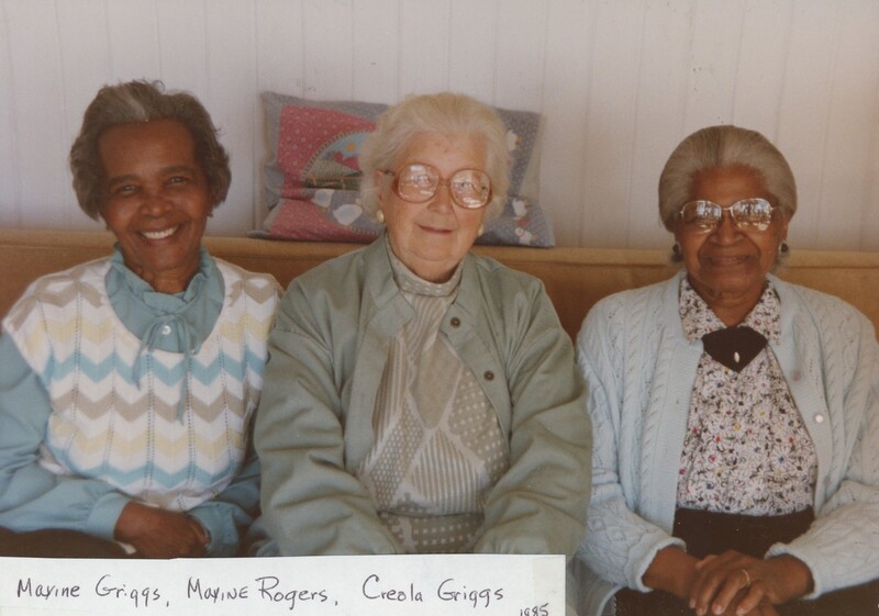 Three older people sat next to each other on a couch smiling.