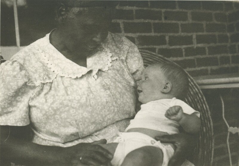 A close up of a person craddling a baby in their arms while they are staring into eachothers eyes smiling.