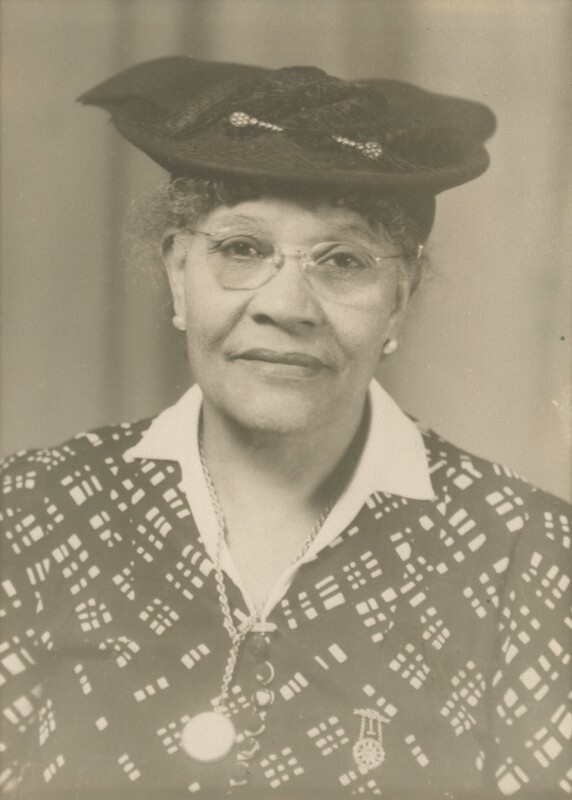 An older people wearing a hat and glasses having a portrait taken from the chest up.