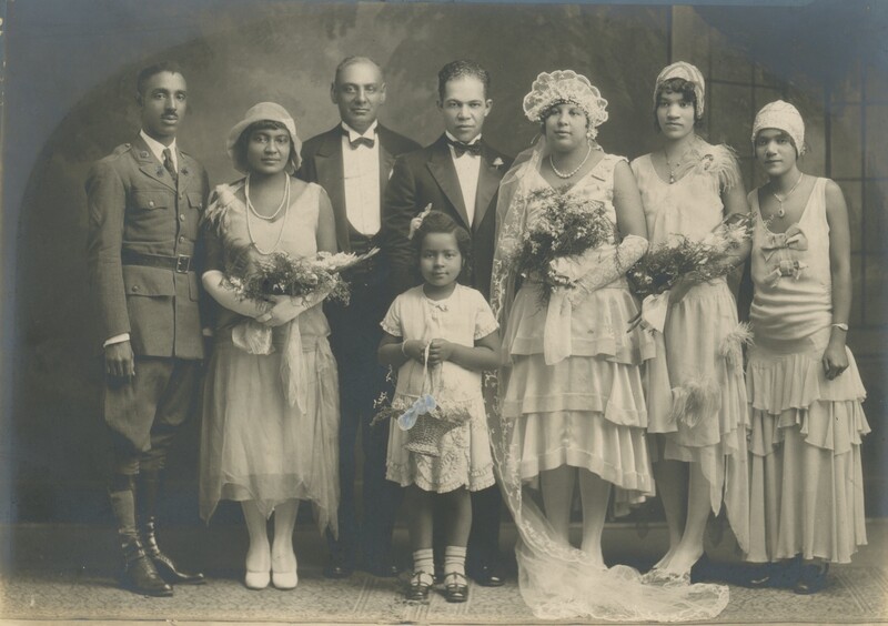 A bride and groom on their wedding day posing for a photo with the wedding party.