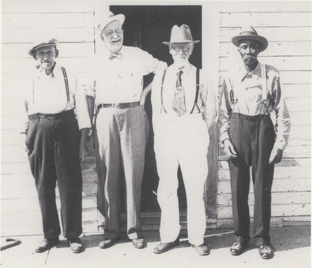 Four people are standing next to eachother in front of a doorway.