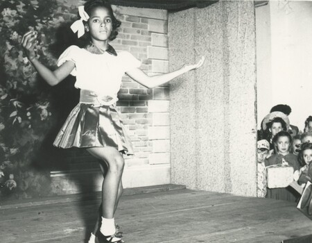A small child performing on a stage for a crowd.