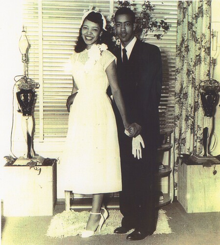 A bride and groom stood next to eachother while holding both hands.