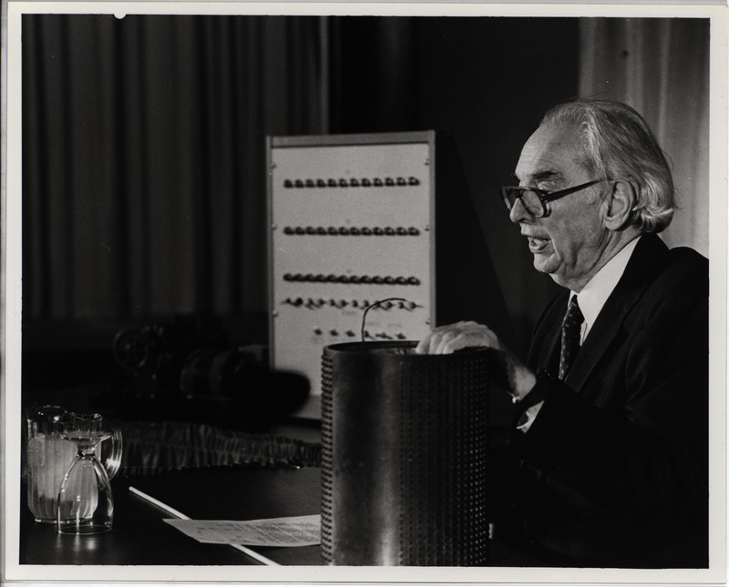 Photograph of J.V. Atanasoff gives a lecture, while holding a memory drum from the Atanasoff-Berry Computer.