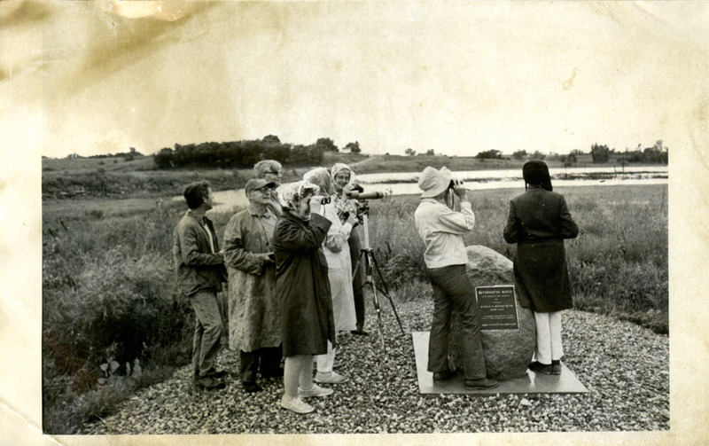 A group of several people, many with binoculars, watch for birds at Hendrickson Marsh.