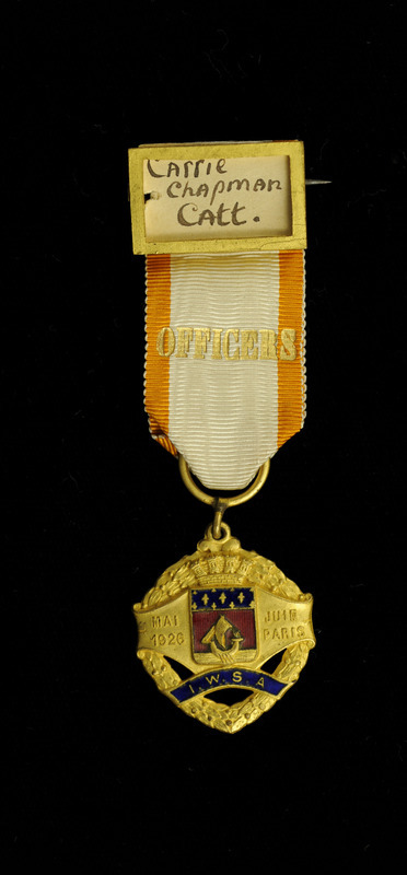 White and gold ribbon with "Officers" inscribed in gold across it. At the top of the ribbon is a gold name plate holding a piece of paper with "Carrie Chapman Catt" hand written on it. At the bottom of the ribbon is a gold medal in an slightly oval shape with "MAI 1926" "JUIN PARIS" in raised letters, blue inlay with "I.W.S.A." inscribed in gold. This is from the Tenth Congress of the International Alliance of Women for Suffrage and Equal Citizenship, which was held in Paris, France, May 30-June 6, 1926.