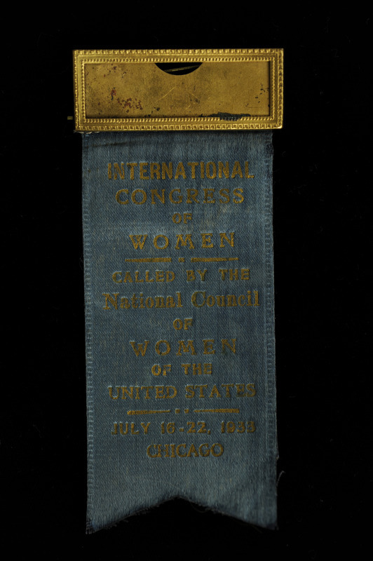 Blue rectangular ribbon with a 'V' cut out of the bottom of the ribbon, with "International Congress of Women" "Called by the National Council of Women of the United States" "July 16-22 1933 Chicago." The top of the ribbon has a gold name plate with no paper insert. The ribbon is from the International Congress of Women for Civil Rights, which was held July 16-22, 1933, Palmer House, Chicago, Illinois.