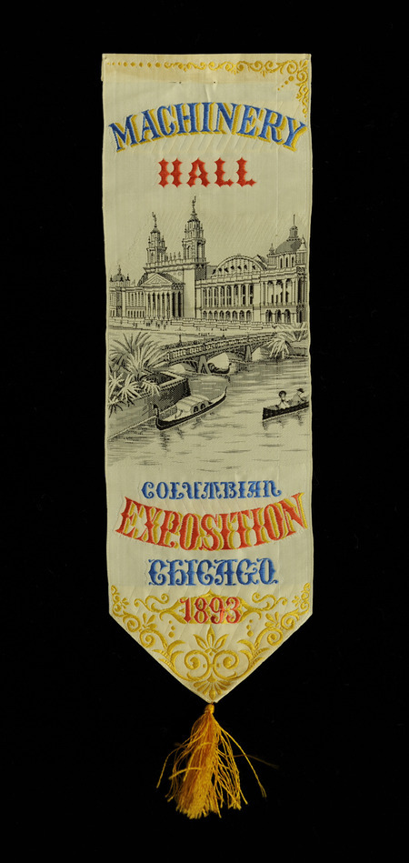White satin and rectangular ribbon has a pointed end with a gold tassel. The ribbon contains an image of a large building behind a river with small boats and a bridge, "Machinery Hall" "Columbian Exposition Chicago 1893" inscribed in blue, orange, and gold.