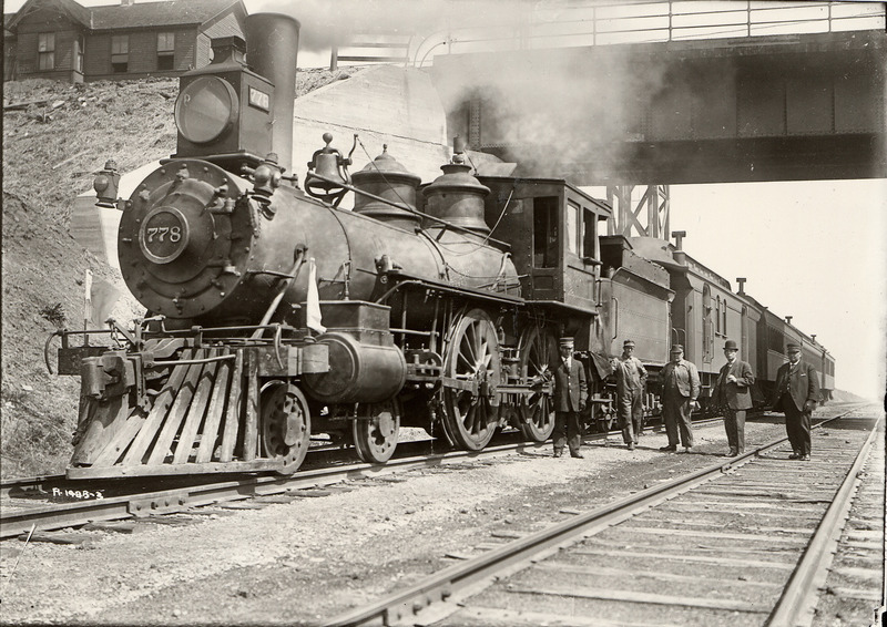 Photograph of a corn train's exterior, with five of the crew standing beside it. Taken in 1910.
