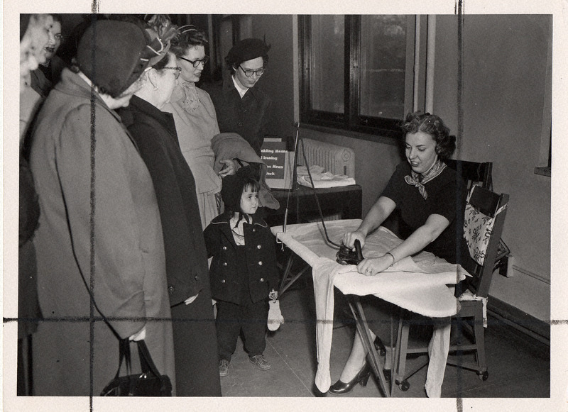 Photograph of a group of women watching how one should iron properly.