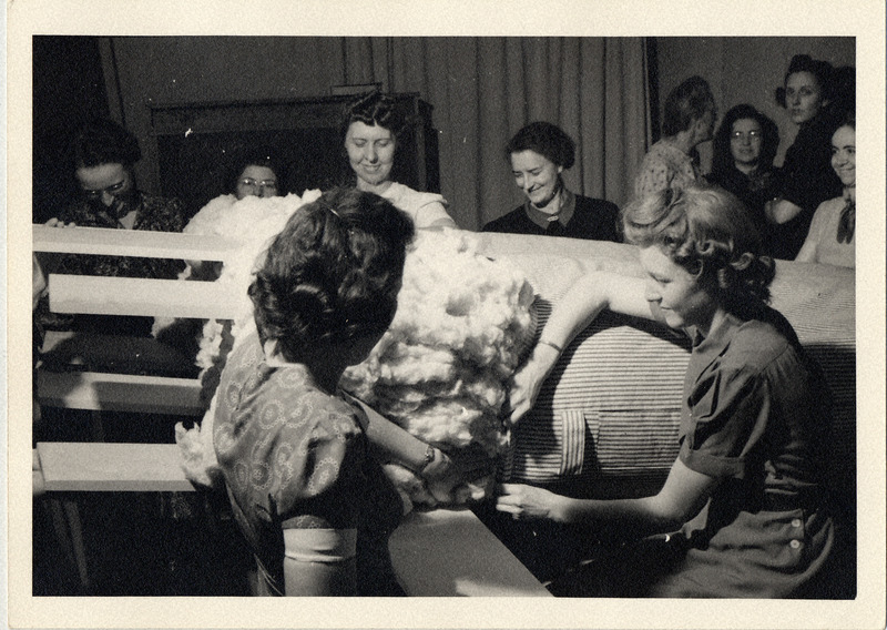Photograph of a group of women stuffing a mattress. Taken in 1940 or 1941.