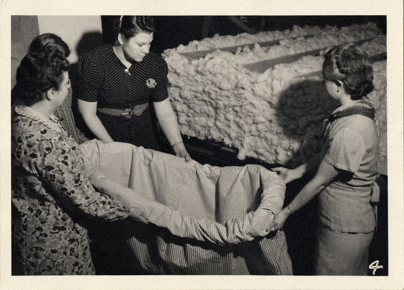 Photograph of three women who are preparing to stuff a mattress. Taken in 1940 or 1941.
