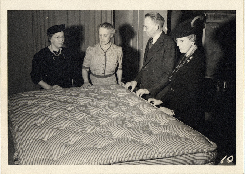 Photograph with a caption that reads: (From left) Mrs. Raymond Sayre, Mrs. Ellis, Director Bliss, and Miss Grace Frysinger inspecting a finished mattress." Taken in 1940-1941.