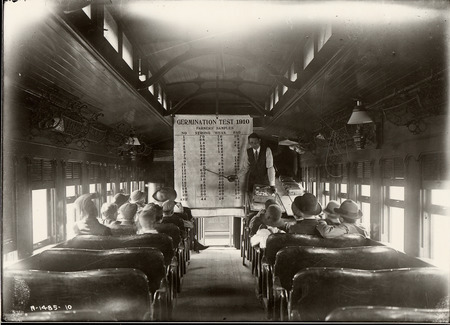 Photograph of a Corn Train interior that is facing the instructor, Ralph (R.K.) Bliss. Taken in 1910.