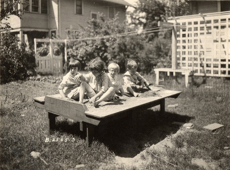 Photograph with a caption that reads: "Four children playing on a makeshift playground in the backyard of Professor McDonald's residence." Taken in 1927.