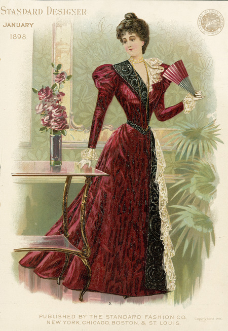 Evening dress, full skirt with fall of lace down side and train, sleeves have shoulder puffs and are fitted to wrist with lace ruffle cuffs, v-shaped neckline, one side of lapel is contrast fabric, the other lace, hair piled on top of head. (published by Standard Designer).