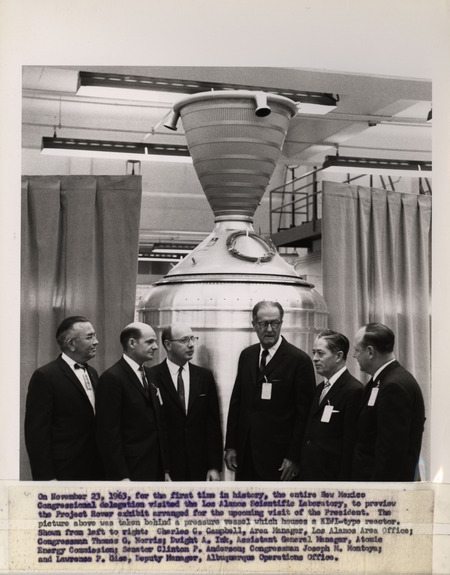 Annotation: "On November 23, 1963, for the first time in history, the entire New Mexico Congressional delegation visited the Los Alamos Scientific Laboratory, to preview the Project Rover exhibit arranged for the upcoming visit of the President. The picture above was taken behind a pressure vessel which houses a KIWI-type reactor. Shown from left to right: Charles C. Campbell, Area Manager, Los Alamos Area Office;Congressman Thomas G. Morris;Dwight A. Ink, Assistant General Manager, Atomic Energy Commission;Senator Clinton P. Anderson;Congressman Joseph M. Montoya;and Lawrence P. Gise, Deputy Manager, Albuquerque Operations office."