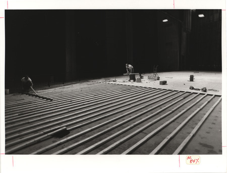 Photograph of two people working on replacing the stage floor in C.Y. Stephens Auditorium.
