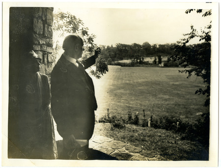 A black and white photograph showing Louis Hermann Pammel pointing to a field while standing in an archway in an unknown Iowa state park.