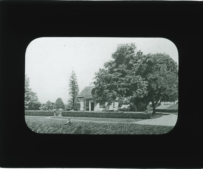 Cottage with trees and shrubs.