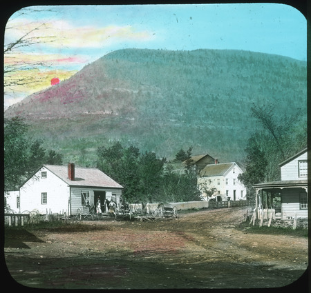 Colored slide showing open space next to houses with mountains and the sun setting.
