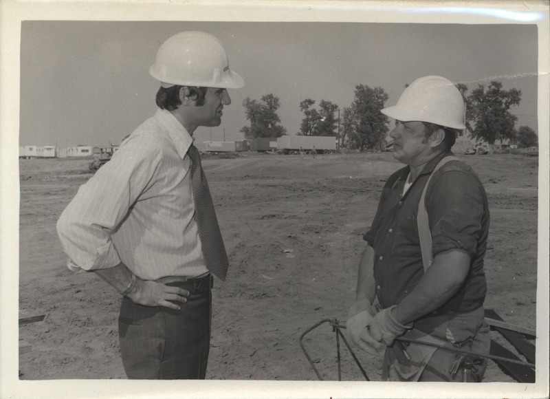 Photograph of Edward Mezvinsky speaking to a construction worker.