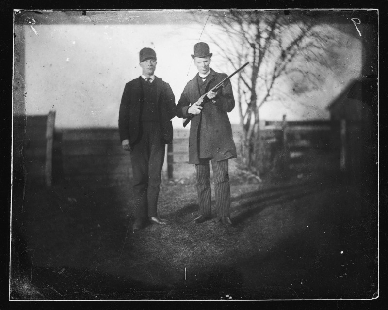 George and Descartes (Dan) Pascal at the John Pascal farm in Pocahontas, Iowa. The man on the right holds a rifle.