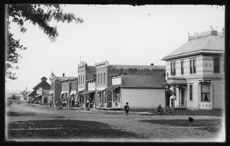 Street scene in Grand Mound, Iowa. Men and boys stand in front of one residential and several commercial buildings.