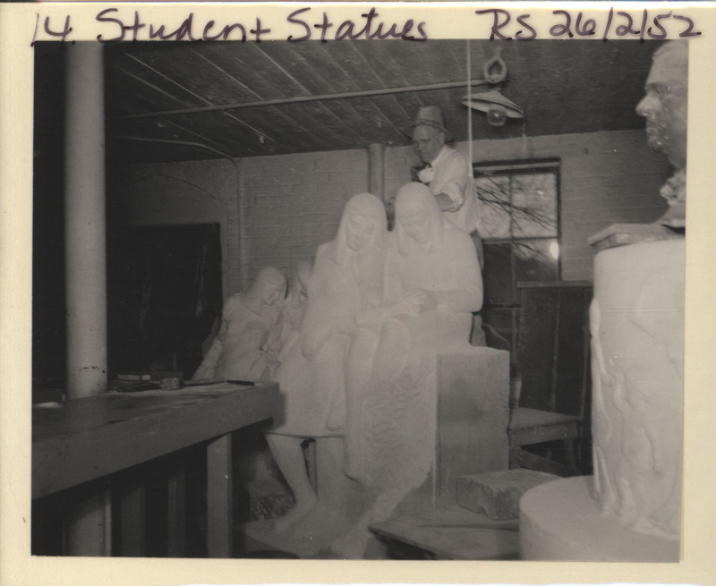 Photograph of the interior of Christian Petersen's studio showing Petersen standing above a sculpture. The sculptures seen include "Conversations," "Joy" fountain, and an unknown male bust.