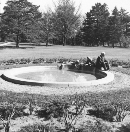 Christian Petersen sitting on Marriage Ring fountain basin (terra-cotta 1942) Located near MacKay Hall. Cco: Silver gelatin photograph on board