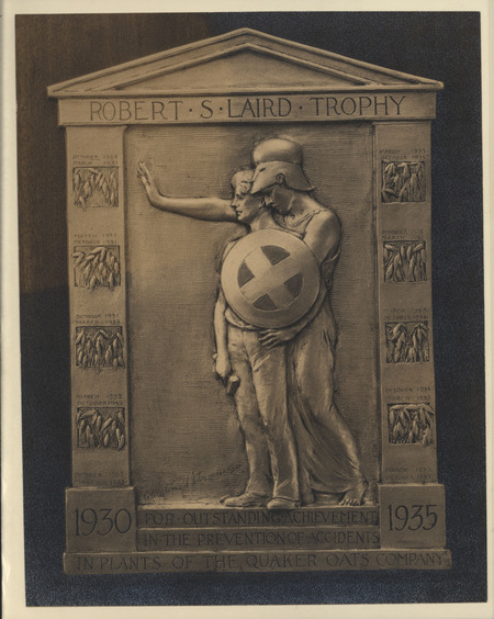 A photograph of bas-relief of the "Robert S. Laird" trophy created by Christian Petersen. The sculpture depicts a figure in Trojan dress protecting a male figure holding a hammer. The bas-relief has places to add inscriptions of the names of future winners.