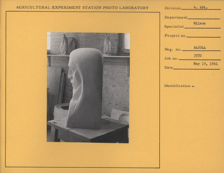 Photograph of Christian Petersen's studio in 1961. the following pieces are visible: "Head of Christ," a robed Christ figure, "Mother and Child," and "Alumni Medallion.".