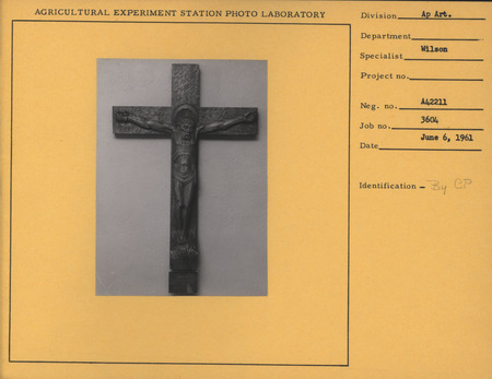 A black and white photograph of a walnut sculpture titled "Christ on the Cross" by Christian Petersen.