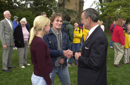 Photograph of President Geoffroy greets two students at a picnic lunch prior to his installation ceremony.