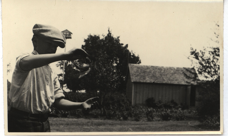 An unidentified boy with a young Rose-breasted Grosbeak suspended from his hand, June 11, 1925. Photograph originally titled "Young Red-breasted Grosbeak held by boy." Rosene provides details on back of photograph.