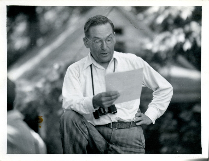 Walter Rosene reading poems from a paper he is holding while on a field trip in McGregor Heights. Photograph originally titled "Walter Rosene reading poems on field trip in McGregor, Iowa." Rosene provides details on back of photograph.