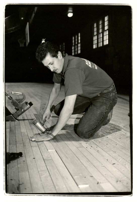 John Tillman is repairing the new State Gymnasium floor. The floor was marred by rollerbladers or skateboarders over a weekend. The photograph appeared in Inside Iowa State on January 13, 1995.