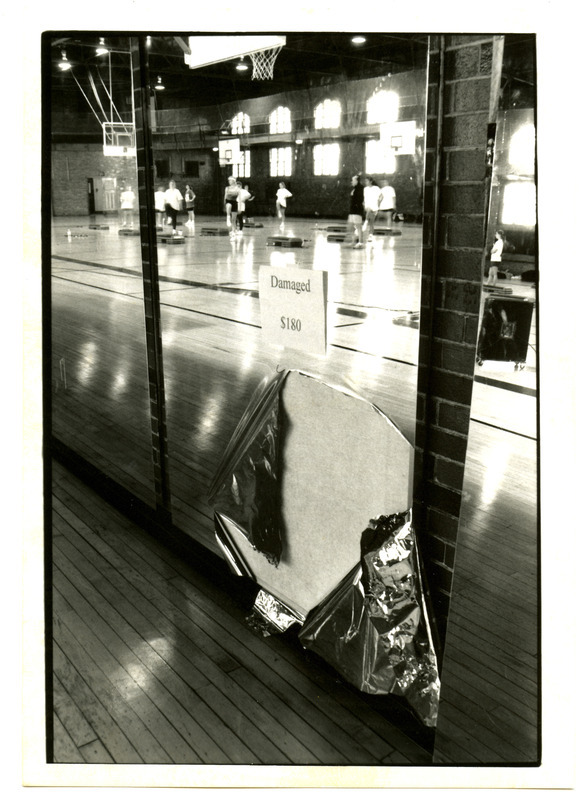 This sign shows the cost of damage to an aerobic mirror torn off the wall of State Gymnasium by vandals. The photograph appeared in Inside Iowa State on February 24, 1995.