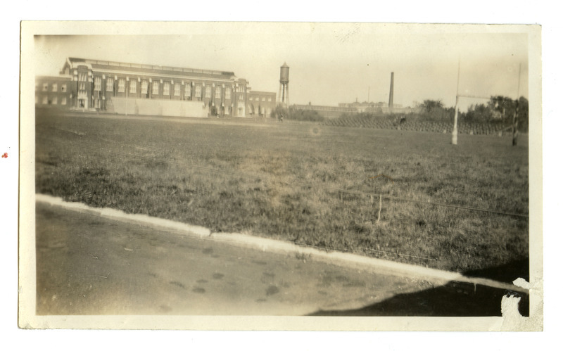 This back (south) view of State Gymnasium shows State Field (Clyde Williams Field.) The goal posts are at the far right and the bleachers line the east side of the field. The Marston Water Tower is at the center of this view.