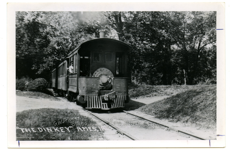 The Ames & Campus Railway (The Dinkey) is traveling along an area bordered with trees. The front of the photograph indicates that it may have been taken during Excursion Days, October 5-6, 1906.